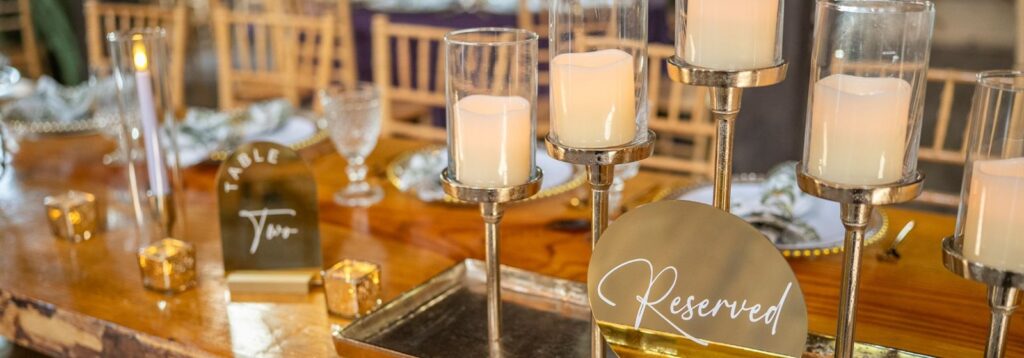 Gold Reserved and Table Two signs with candles on a rustic wooden wedding table at The English Country Barn